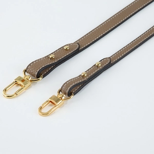 Detail of lychee pattern leather shoulder strap with gold lobster clasp and rivets