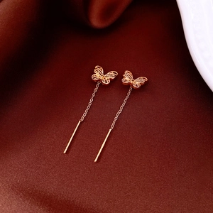 Detailed close-up of 18K gold plated butterfly earrings on elegant red silk fabric