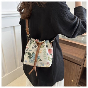 Detailed embroidery on a canvas drawstring bucket bag with premium brown leather strap
