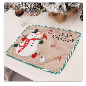 Close-up of burlap Christmas placemat featuring snowman embroidery and festive green border