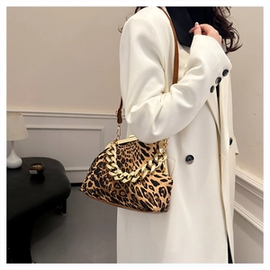 Detail of leopard print shell bag featuring a thick gold chain and brown leather strap