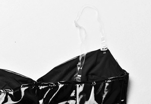 Detail of black glossy PU bodysuit showing adjustable transparent shoulder straps