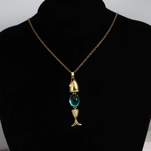 Detail of a gold fish pendant necklace with a green gemstone and pearl on a black mannequin