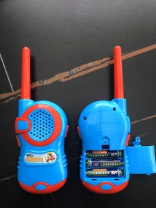 Detail of toy walkie talkie open battery compartment showing 3 AAA batteries inside