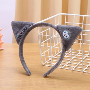 Close-up of gray plush cat ear headband featuring embroidered logo and owl character