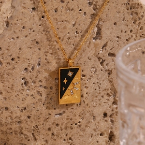 Close-up of gold rectangular necklace with black enamel sun and star celestial design