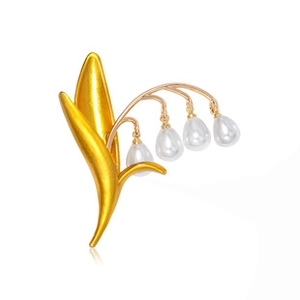 Close-up of golden Lily of the Valley brooch with elegant white drop-shaped pearls