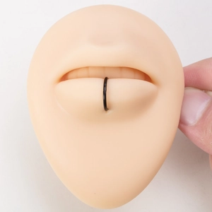 Black stainless steel hinge hoop ring on silicone lip piercing practice model