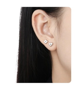 Close-up of S925 sterling silver clover and heart stud earrings worn by a model