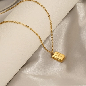 Macro shot of gold-plated Bible pendant with cross engraving on delicate chain