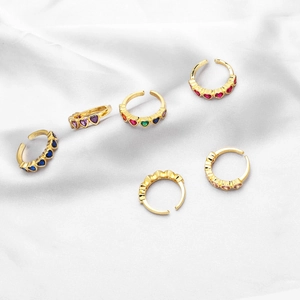 Detailed close-up of adjustable gold heart rings with colorful zircon on satin fabric