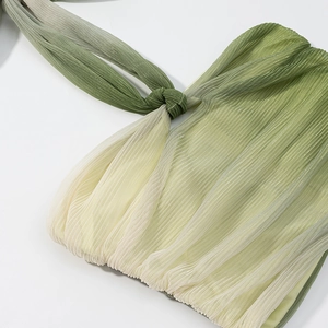 Detail of green gradient plissé fabric with pleated texture and stylish shoulder knot design