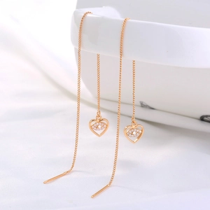 Detailed close-up of gold heart and evil eye tassel earrings with sparkling crystals
