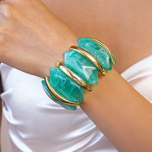 Détail macro du bracelet élastique en acrylique marbré vert et barres dorées