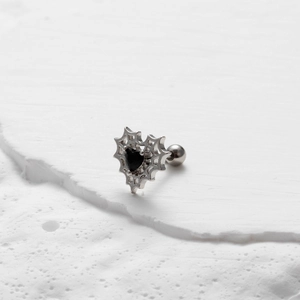Orecchino a ragnatela con zircone a cuore nero su sfondo bianco materico