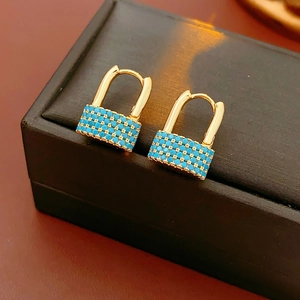Detailed macro shot of gold padlock earrings inlaid with vibrant turquoise stones