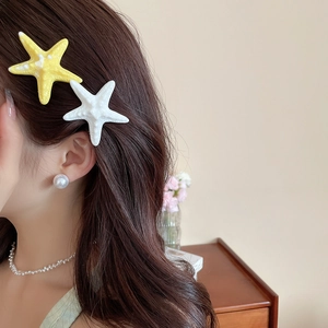 Starfish hair clips and pearl jewelry set shown worn on a model in a cozy indoor setting