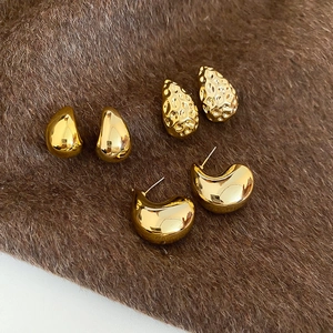 Macro shot of three pairs of textured gold droplet earrings on brown plush background