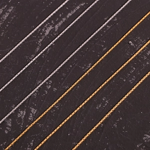 Detailed macro view of 18K gold and silver stainless steel box chains on dark background