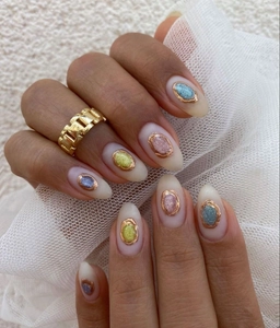 Detailed close-up of almond-shaped nail wrap featuring multi-color glitter and gold border