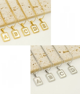 Detail of 18K gold and silver stainless steel shell initial necklaces with pearl inlay