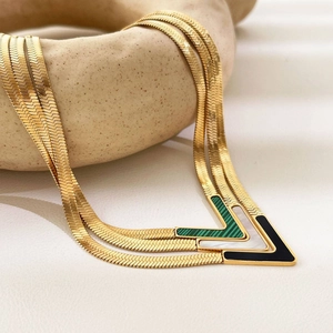 Three gold-plated V-shaped pendant necklaces with green, white, and black stones on snake chains