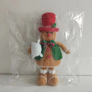 Detail of Christmas gingerbread man doll with knitted texture and red top hat decoration