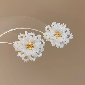 Macro shot of handmade white and gold beaded flower earrings with fine craftsmanship