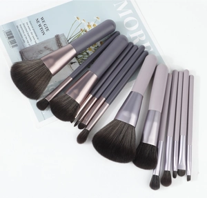 Detailed flat lay of 14 professional makeup brushes with rose gold ferrules and grey bristles