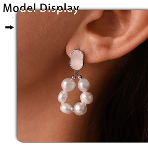Detail view of a model wearing elegant white freshwater pearl dangle earrings