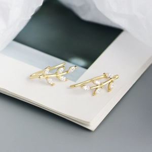 Macro shot of gold leaf-shaped clip-on earrings with shimmering crystal accents