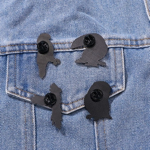 Set of four black metal cartoon bird pins attached to a blue denim jacket pocket