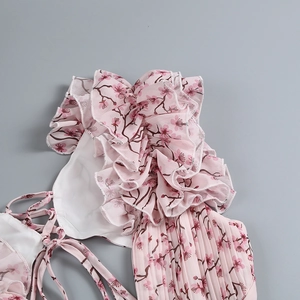 Détail d'une robe en mousseline rose à fleurs avec volants et finitions plissées