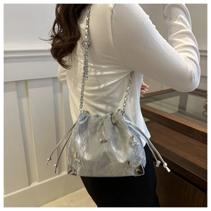 Close-up of silver bucket bag with 3D butterfly charms and metallic pleated texture