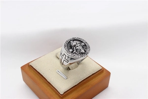 Close-up of vintage steel cross ring with embossed Jesus crown of thorns on beige stand