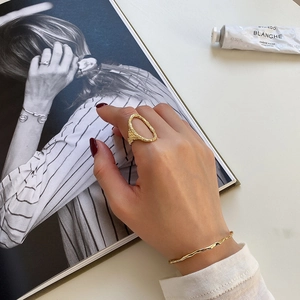 Close-up of golden irregular textured ring and wavy bangle worn for a chic lifestyle look