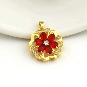 Macro shot of gold heart flower pendant with red zircon petals and micro-pave crystals