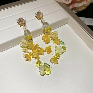 Detail of yellow resin floral earrings with crystal studs and cascading beads decoration