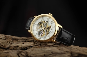 Macro detail of skeleton mechanical watch with golden case and Roman numeral white dial