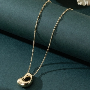 Polished gold bubble letter pendant necklace with organic hollow bean design on dark background