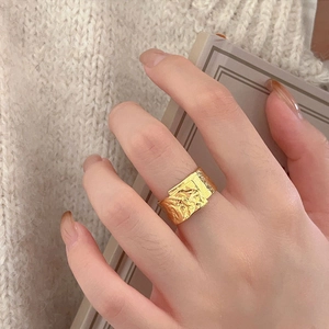 Macro shot of wide gold textured ring with lava finish and side-set gemstones