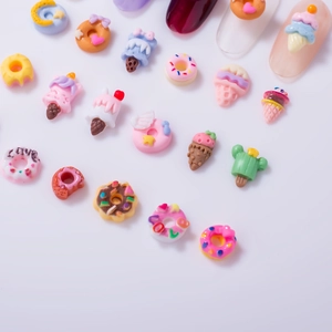 Detailed close-up of resin nail art charms featuring colorful donuts and ice cream shapes