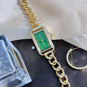 Detail of luxury gold chain watch with green dial and sparkling diamond-set square case