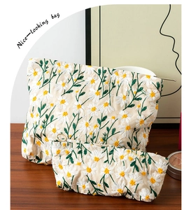 Close-up of daisy embroidery on off-white canvas makeup bag set with zip closure