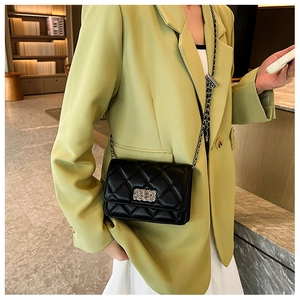 Mini black quilted chain bag with silver lock worn with a stylish lime green blazer