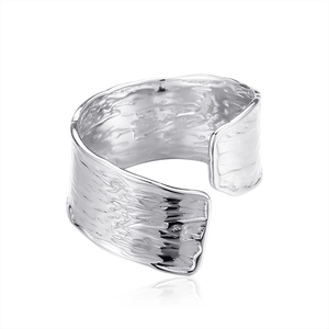 Macro view of wide silver open ring with irregular bark-like texture and industrial style