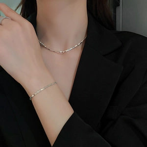 Elegant geometric silver necklace and bracelet set on a model in a black suit