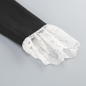 Detail of layered white lace cuffs on black fabric with intricate floral embroidery