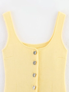 Détail du débardeur en tricot jaune avec larges bretelles et boutons métalliques argentés