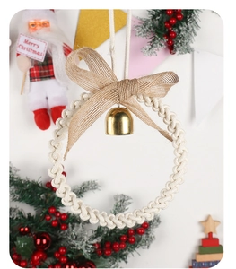 Detail of hand-woven beige Christmas wreath featuring a gold bell and burlap bow